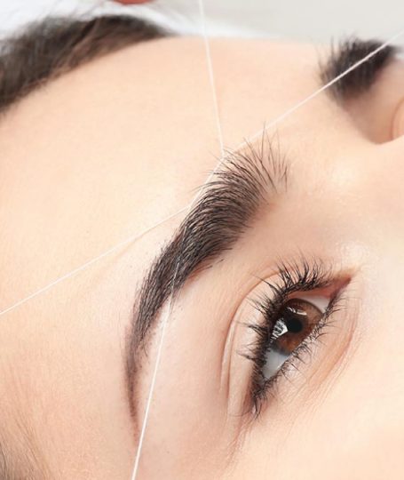 Una donna che si sta depilando le sopracciglia con la tecnica del filo arabo.