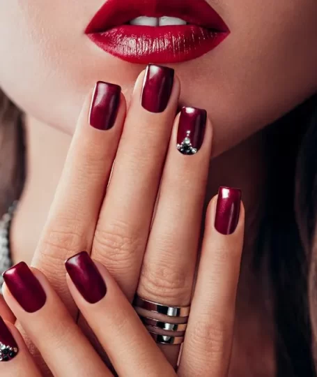 Modella che mostra il suo smalto color bordeaux.